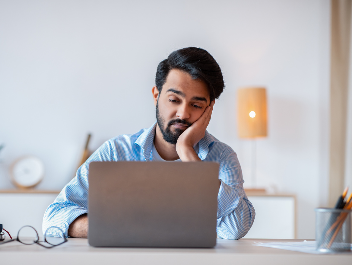 Boring Work. Arab freelancer guy working on laptop with bored face expression